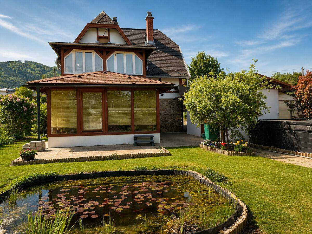 Sonniger Garten mit Teich, Wintergarten und gepflegtem Rasen.