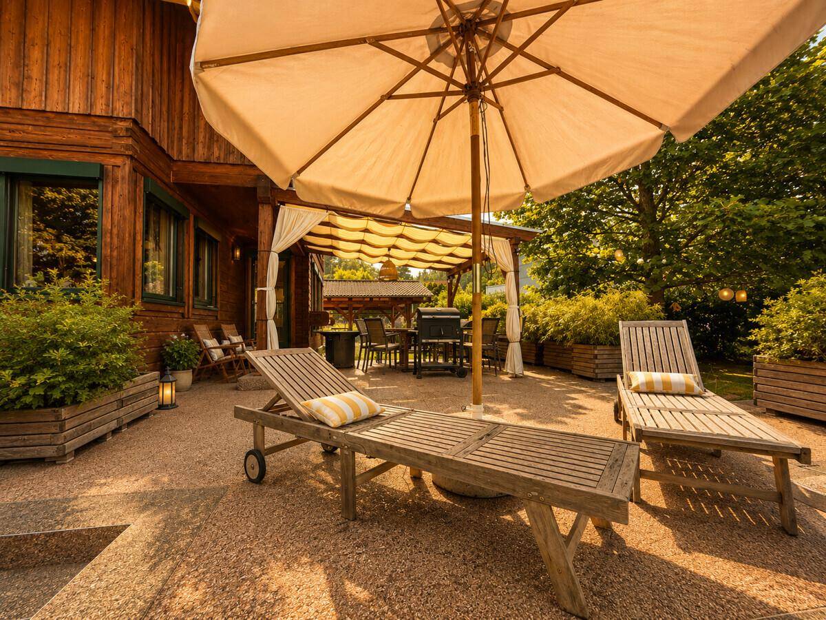 Sonnige Terrasse mit Liegestühlen und großem Sonnenschirm, ideal zum Entspannen.