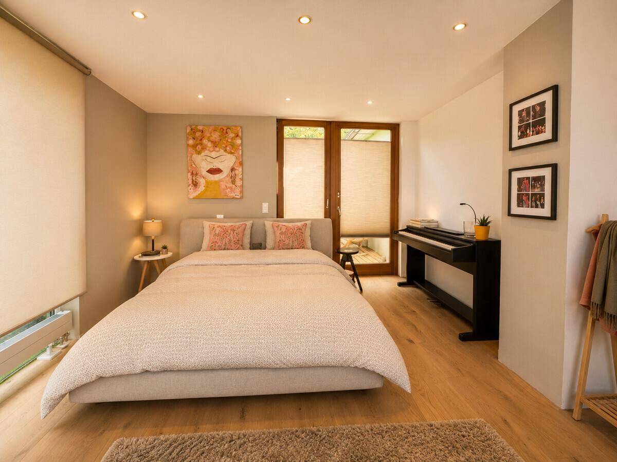 Modernes Schlafzimmer mit Doppelbett, Holzboden und Zugang zu einem Außenbereich.