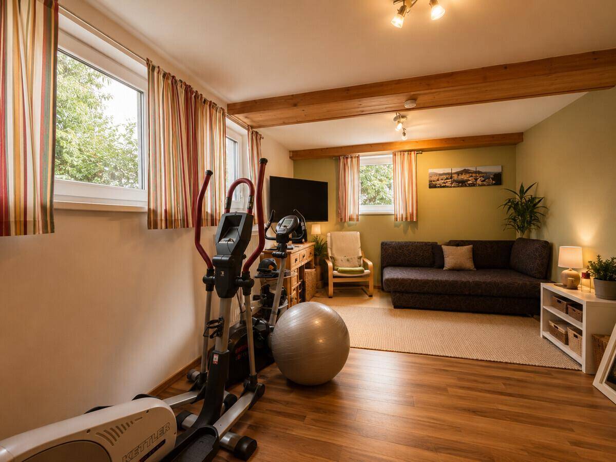 Fitnessraum mit Trainingsgeräten und einer gemütlichen Sitzecke.