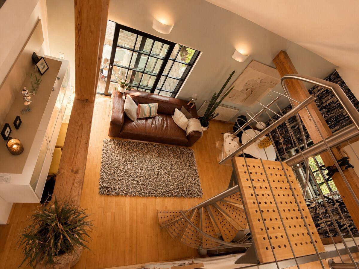 Blick von oben auf den offenen Wohn- und Essbereich mit Wendeltreppe und Ledersofa.