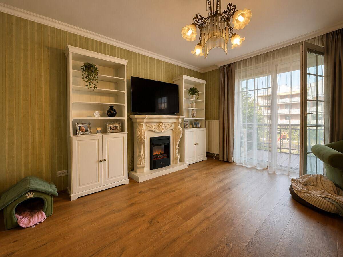 Helles Wohnzimmer mit Kamin, Bücherregalen und Zugang zu einem Balkon.