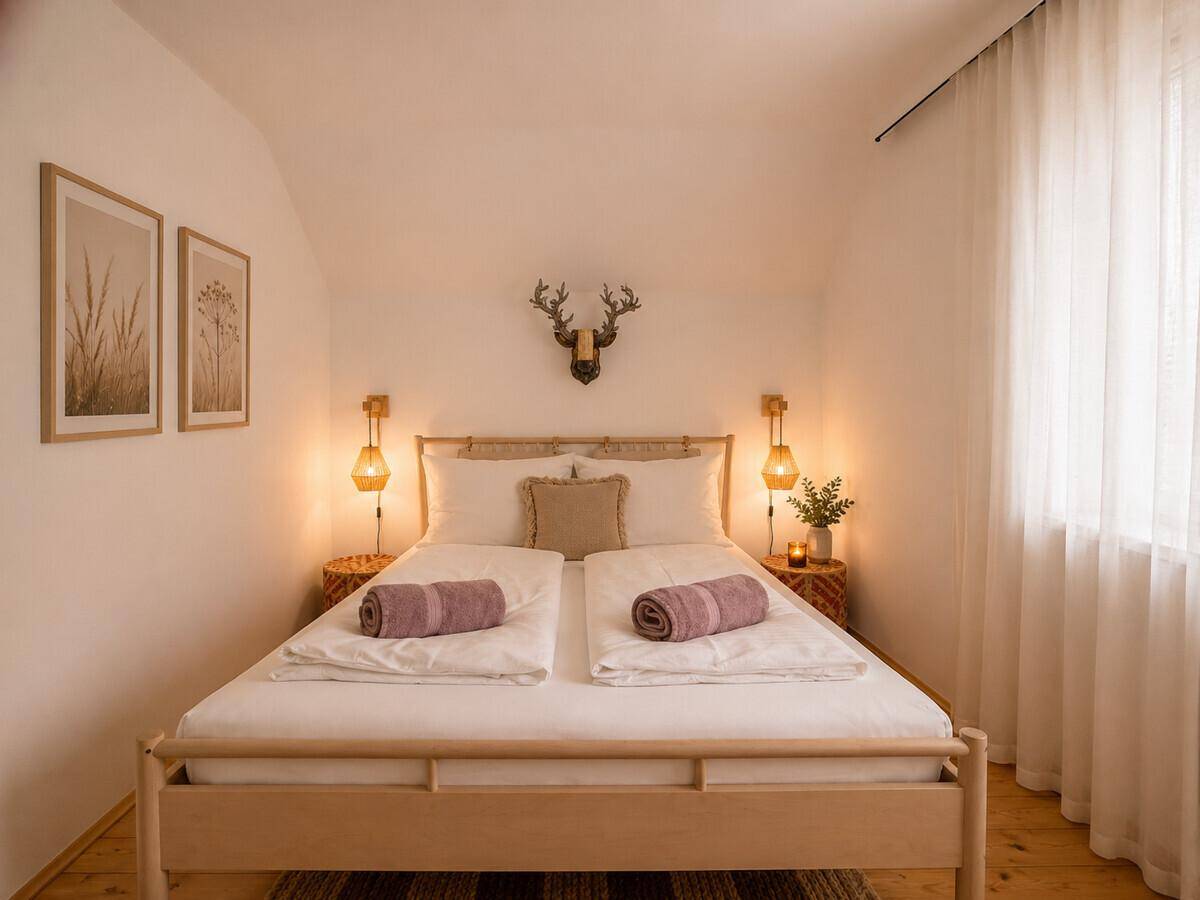 Helles Schlafzimmer mit Doppelbett, Nachttischen und Hirschgeweih-Dekoration.