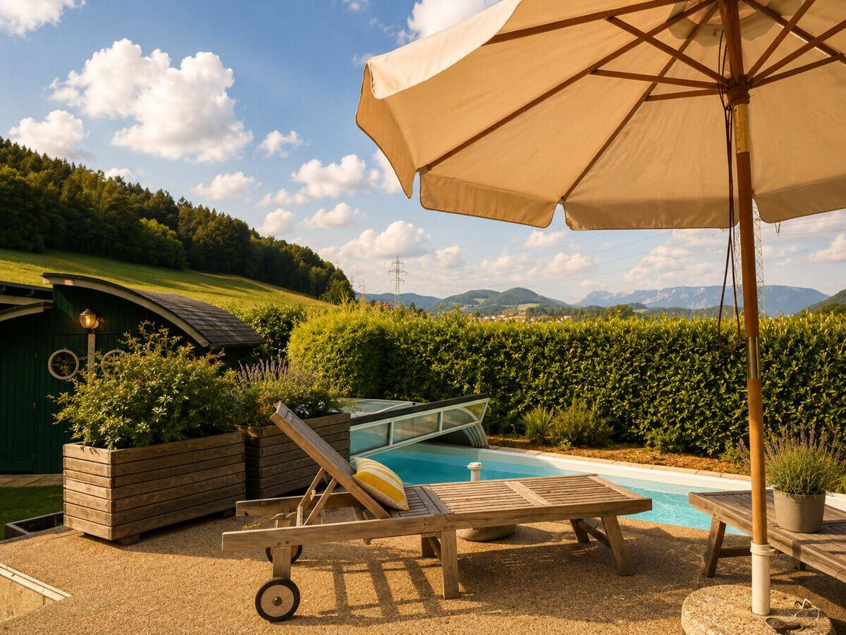 Entspannender Poolbereich mit Liegestühlen, Sonnenschirm und weitem Blick auf die Berge.
