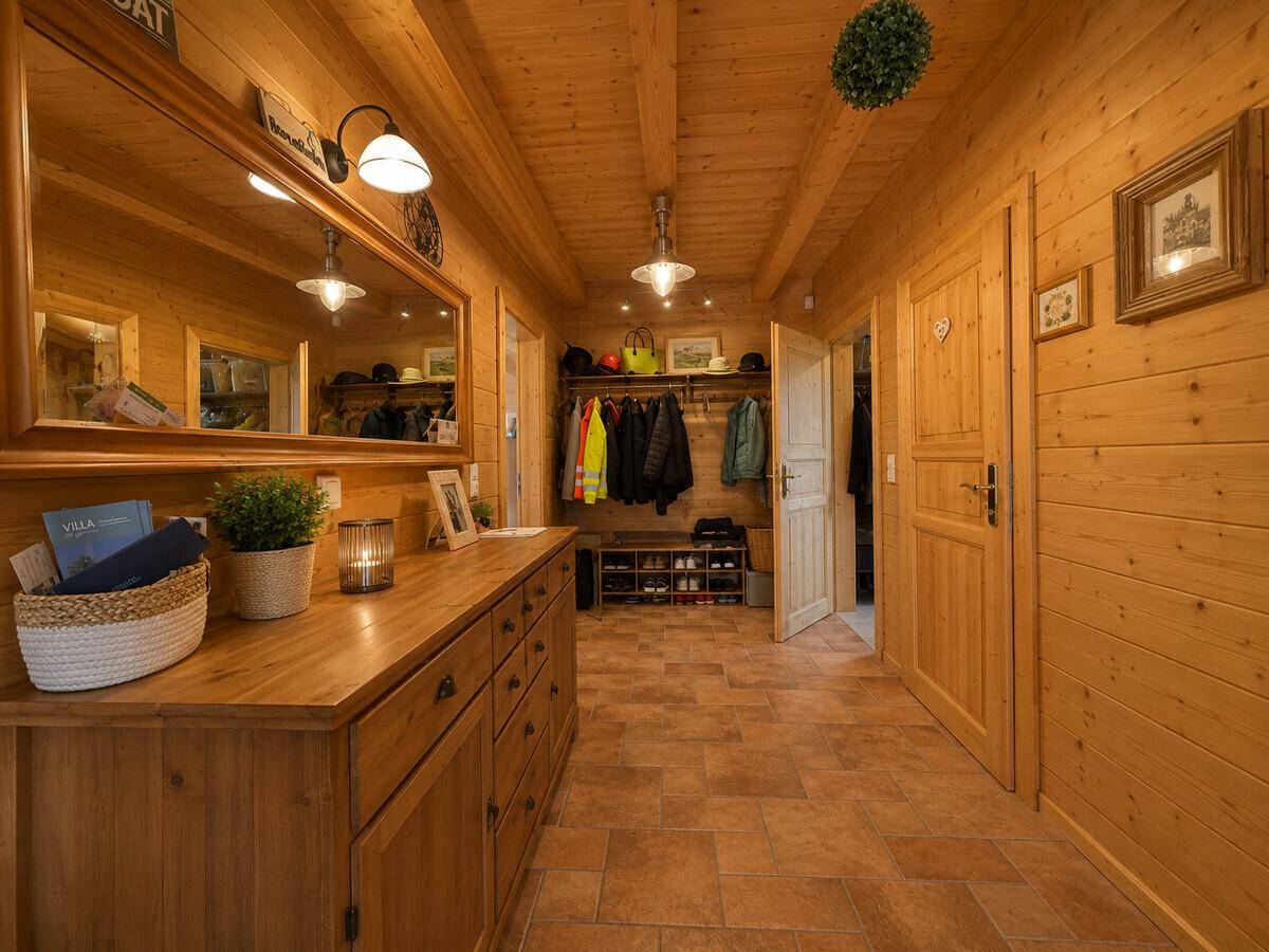Rustikaler Eingangsbereich mit Holzwänden, großer Kommode, Spiegel und Garderobe.