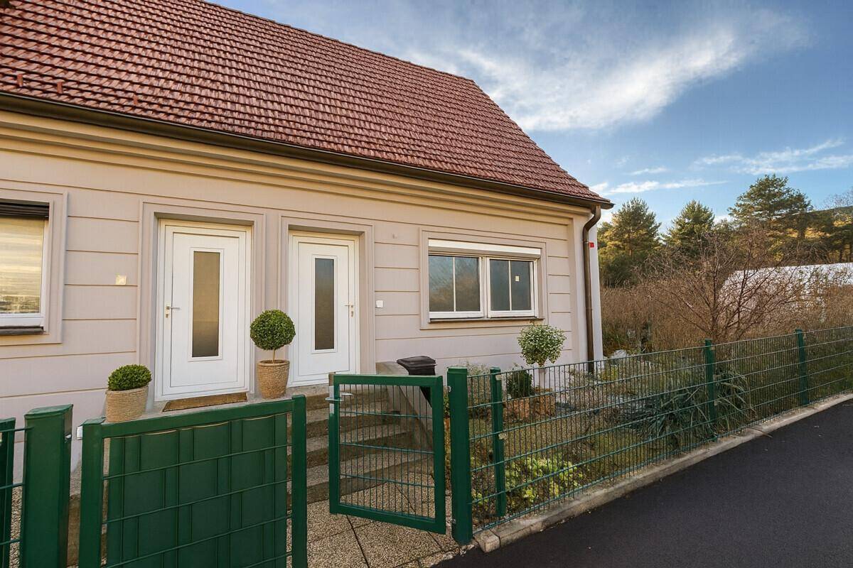 Einfamilienhaus mit zwei Eingängen, gepflegtem Vorgarten und rotem Ziegeldach.