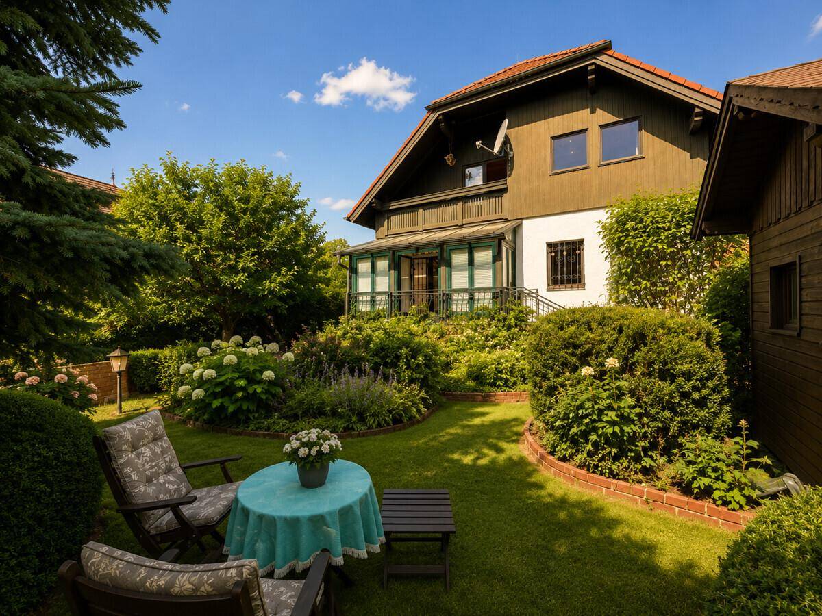 Idyllischer Gartenbereich mit Rasenfläche, Blumenbeeten und einer einladenden Sitzecke vor dem Haus.