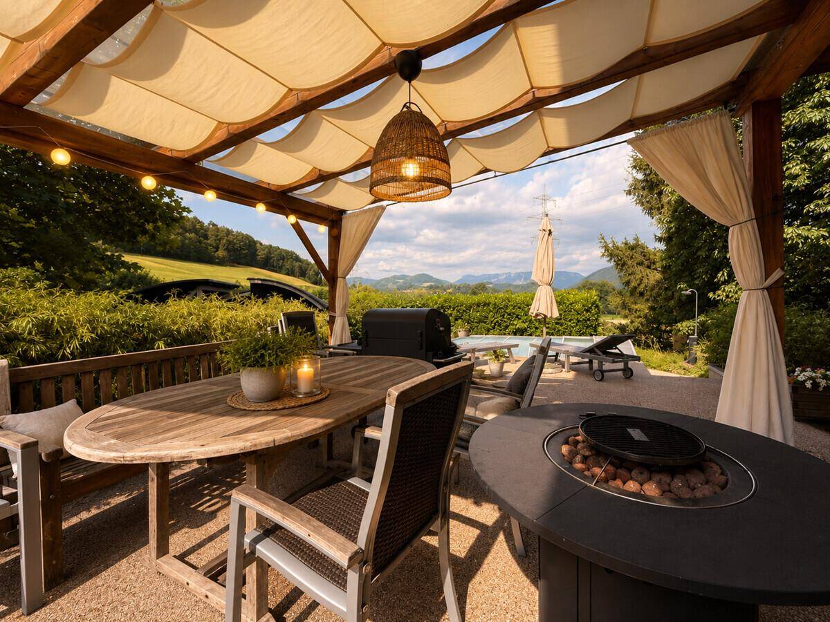 Gemütliche überdachte Terrasse mit Esstisch, Grillbereich und weitem Blick auf die Landschaft.