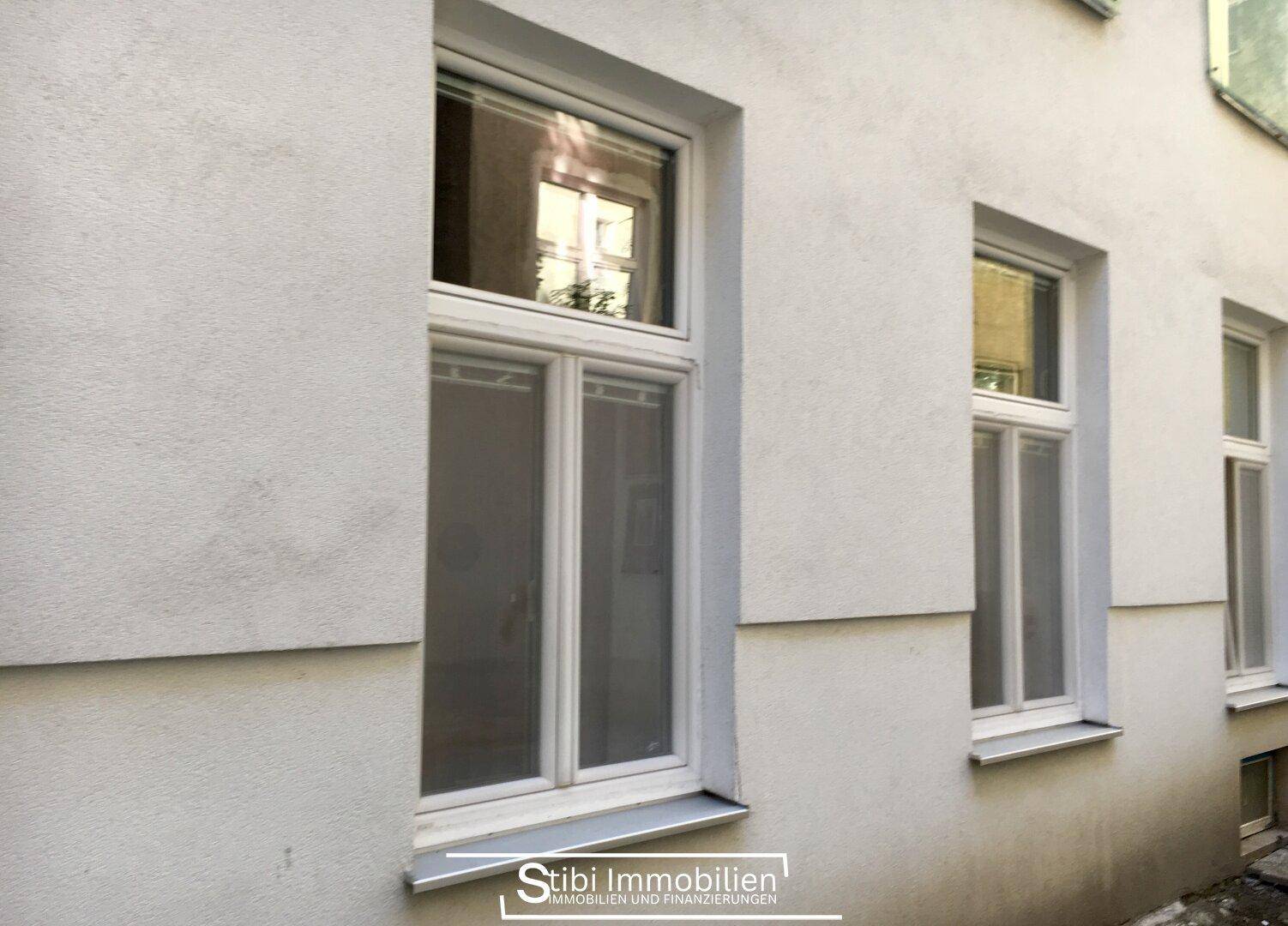 Helle Fassade eines Gebäudes mit mehreren Fenstern, die den Zustand des Altbaus zeigen.