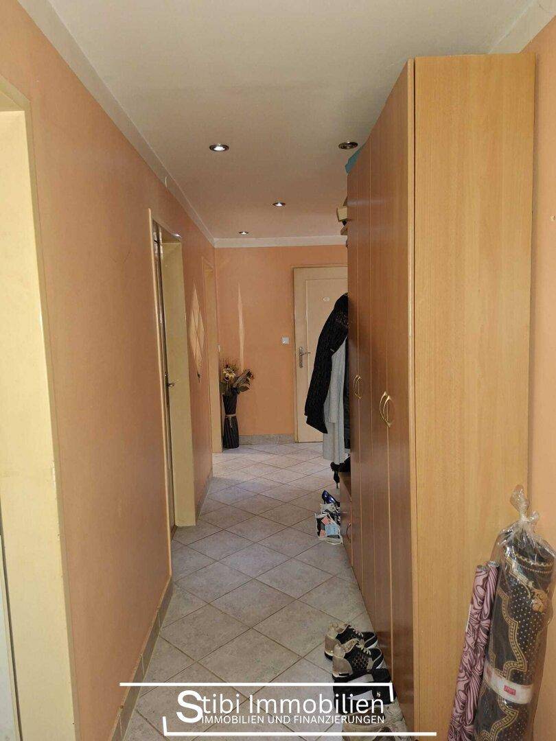 Langer Flur mit Fliesenboden, Garderobe und Türen zu weiteren Räumen.