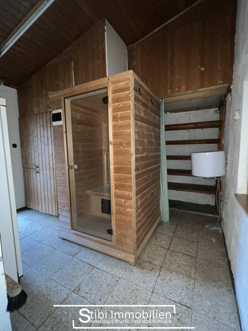 Raum mit einer Holzsauna und Fliesenboden, umgeben von Holzverkleidungen.