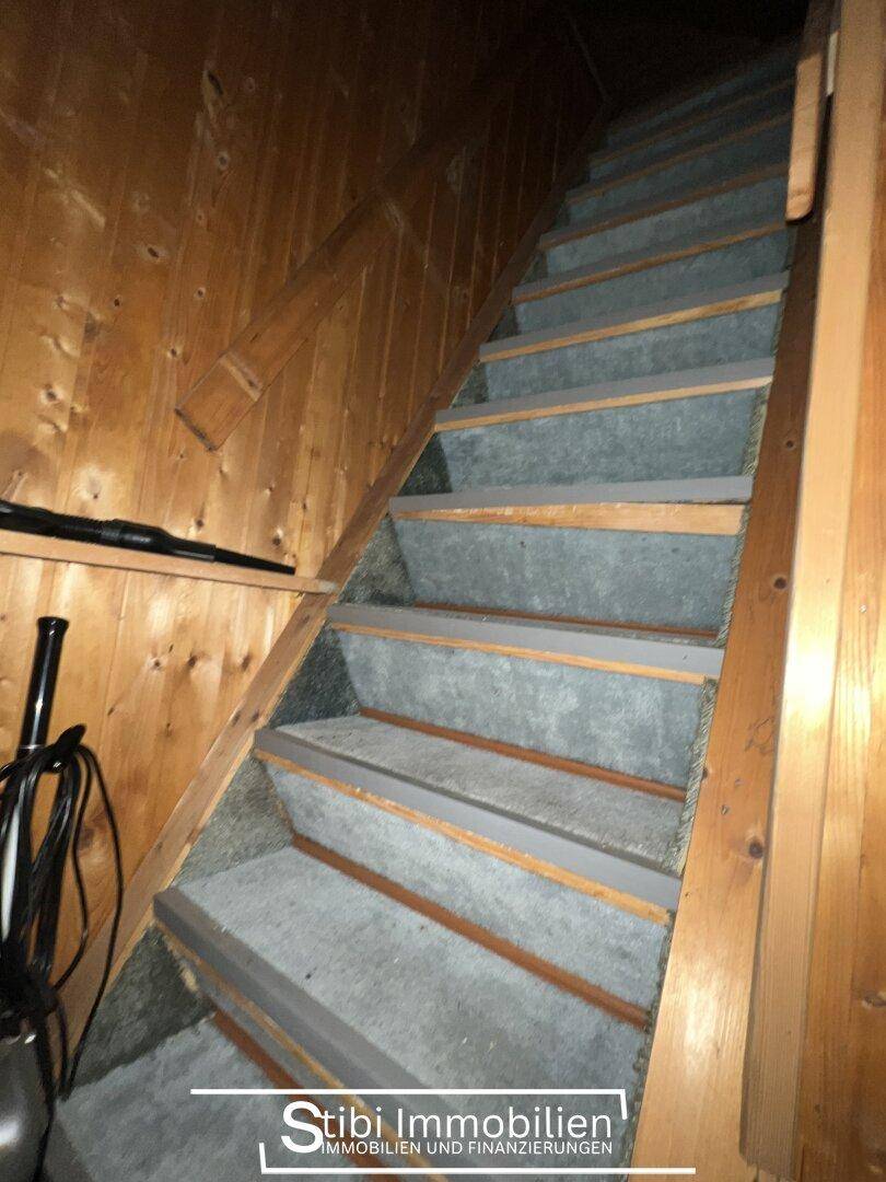Holztreppe mit Teppichstufen und Holzverkleidung an den Wänden.