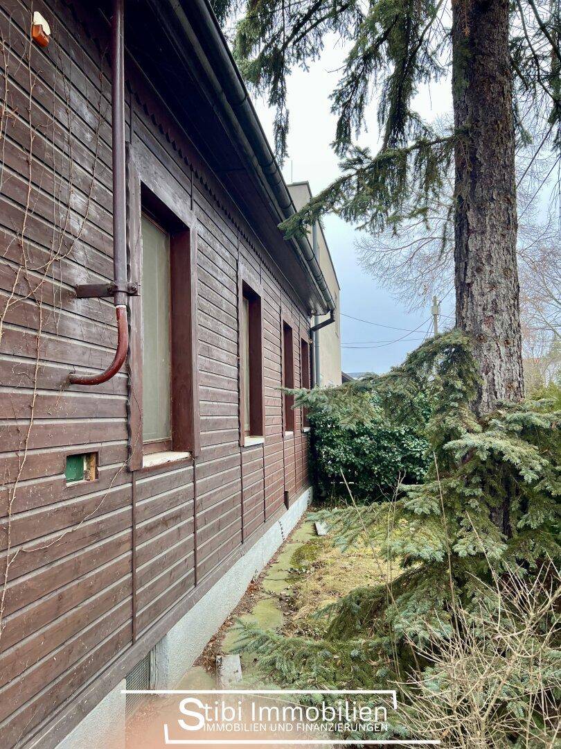 Detailansicht der Holzfassade des Hauses mit Fenstern und Regenrinne.