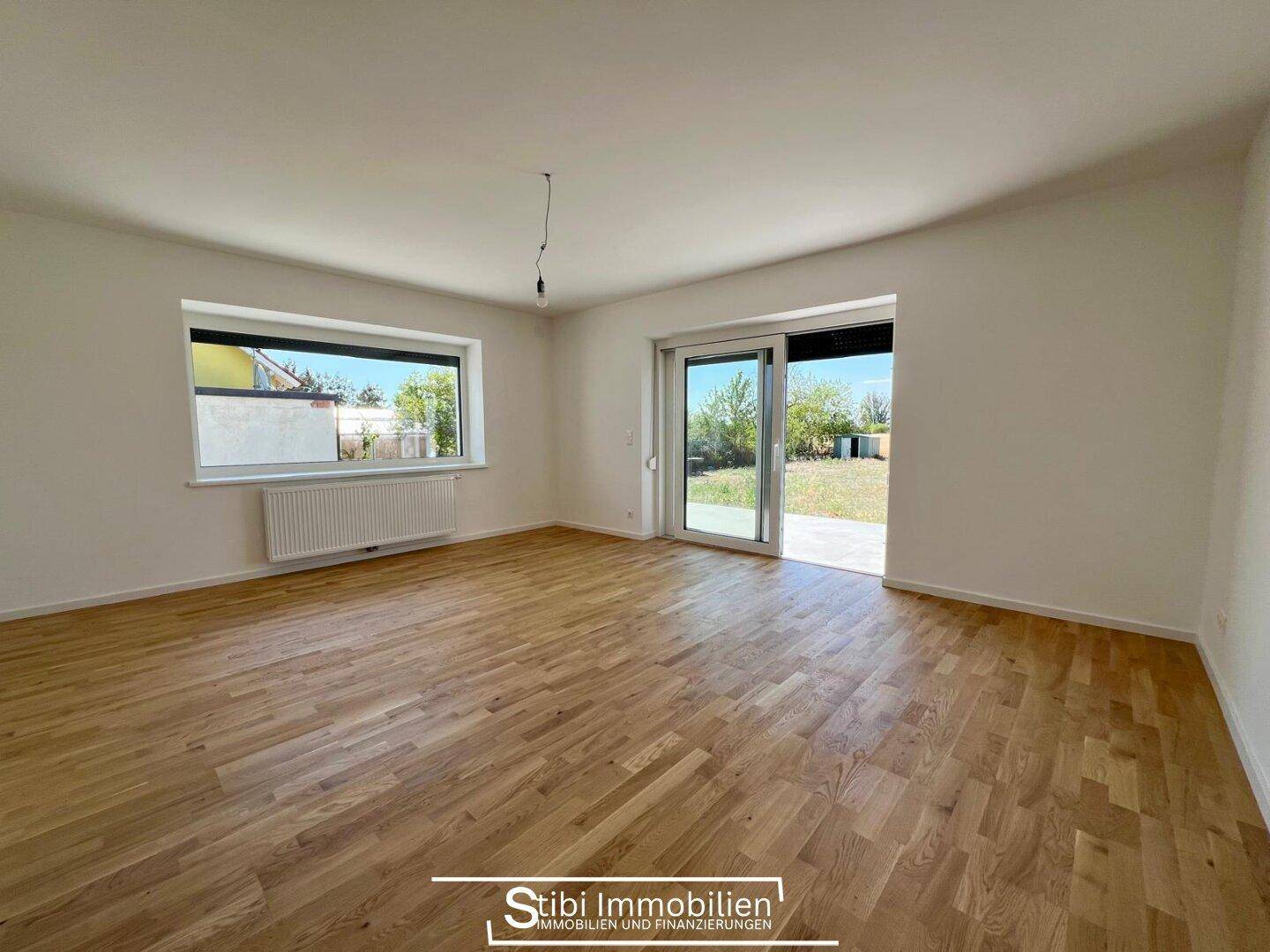 Geräumiges Wohnzimmer mit Holzboden, Schiebetür zum Garten und viel natürlichem Licht.