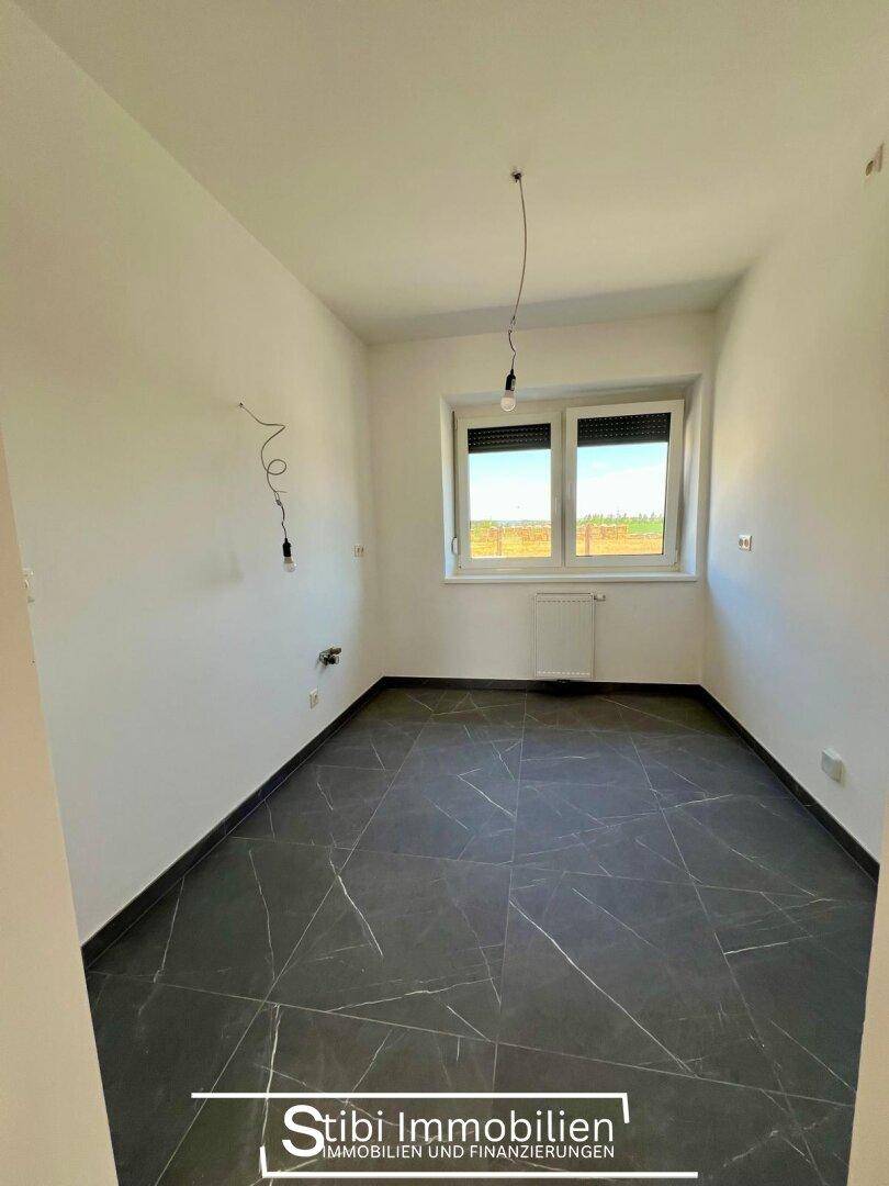 Leeres Zimmer mit modernen dunklen Fliesen und Fenster mit Blick ins Grüne.