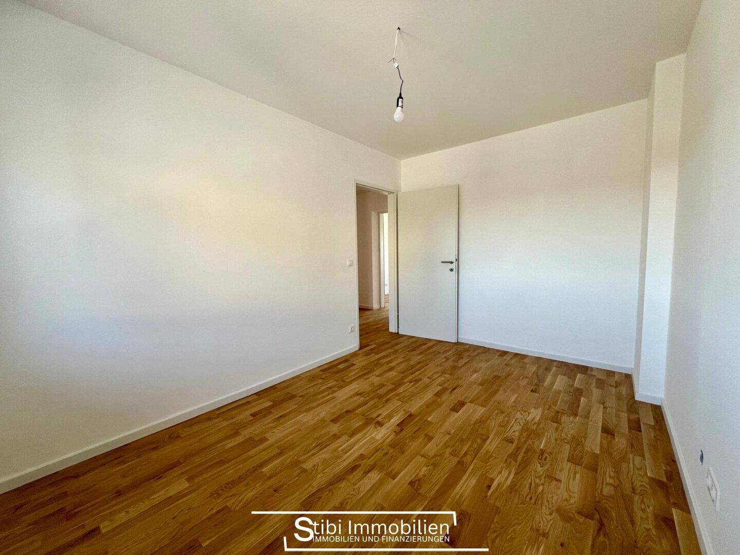 Helles Schlafzimmer mit neuem Holzboden und weiß gestrichenen Wänden, bereit zum Einrichten.