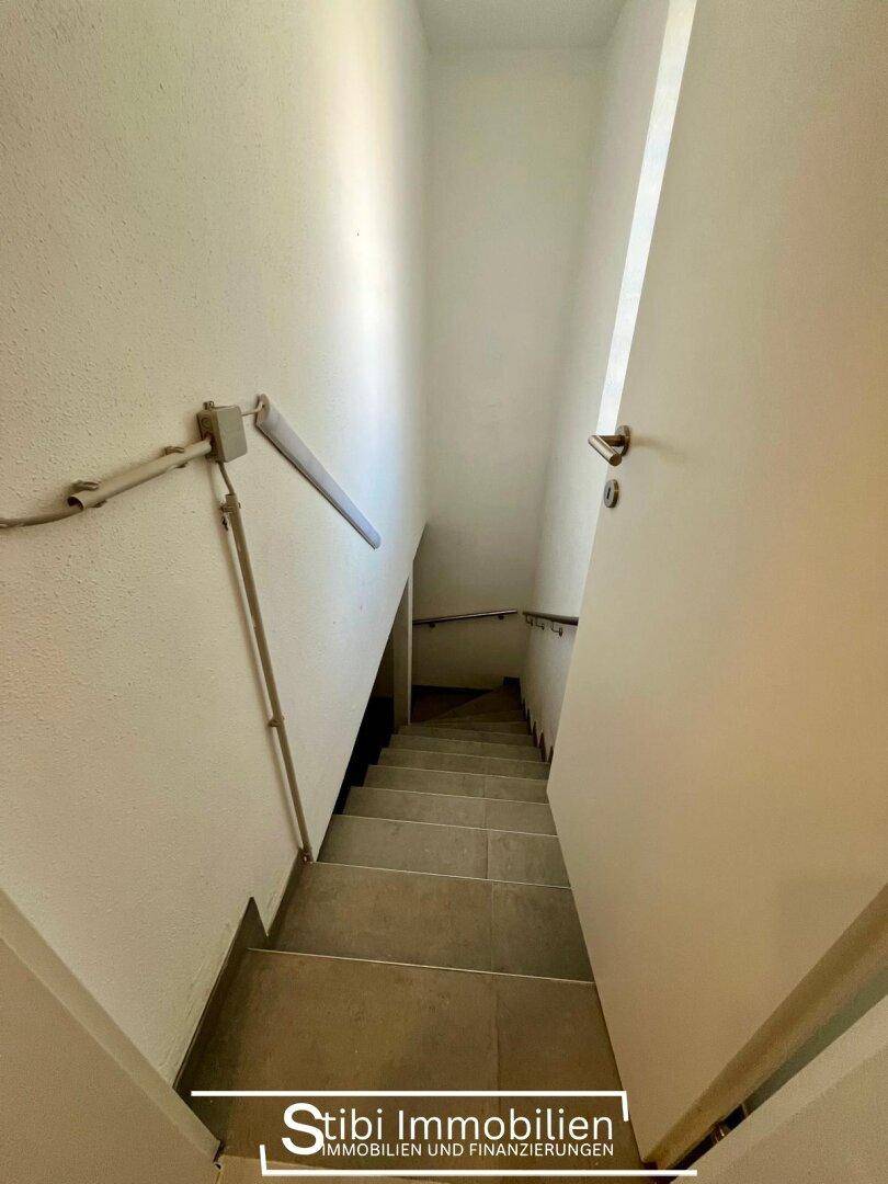 Treppenhaus mit Fliesenstufen und Handlauf, das die verschiedenen Ebenen des Hauses verbindet.