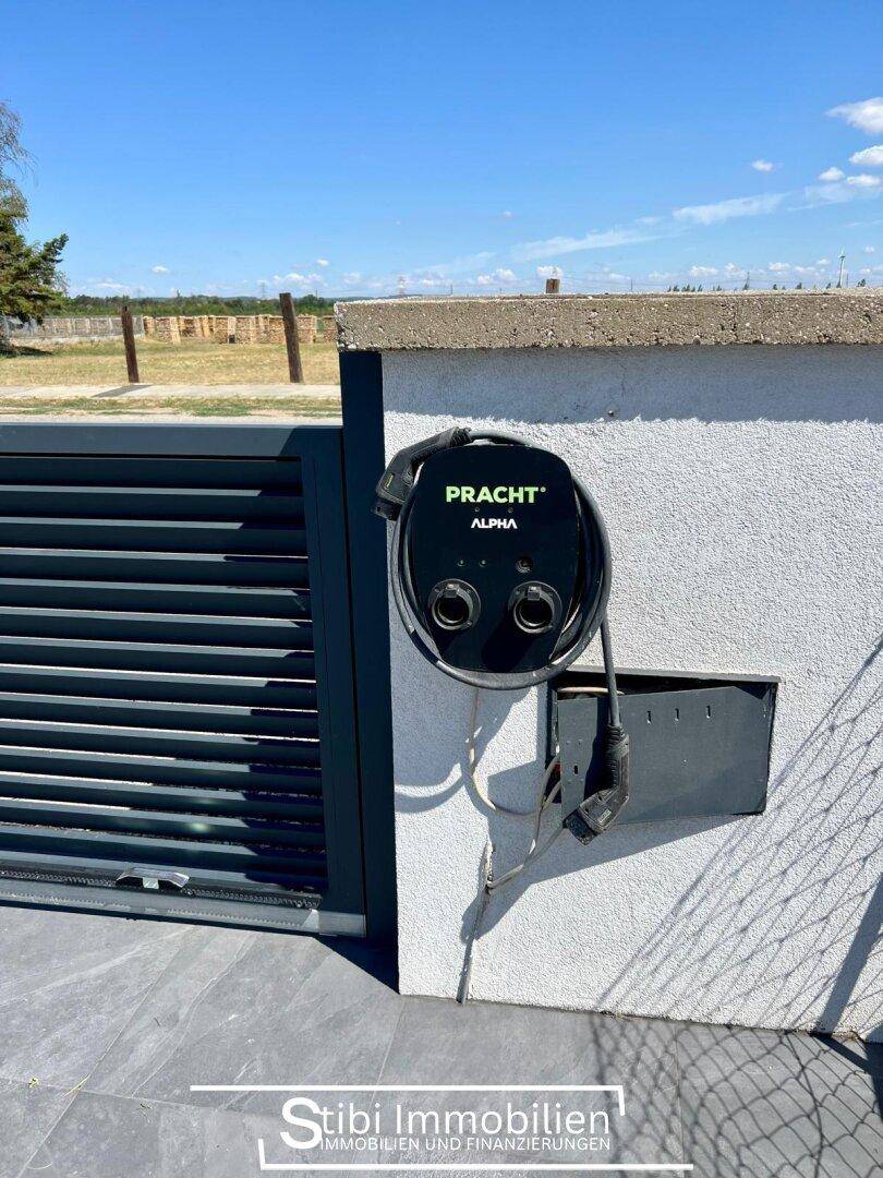 Ladestation für Elektrofahrzeuge an der Außenwand des Hauses, neben dem Eingangsbereich.