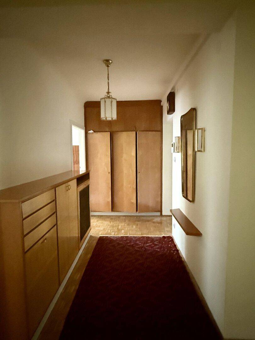 Heller Flur mit Holzboden, Einbauschränken und einem Spiegel an der Wand.