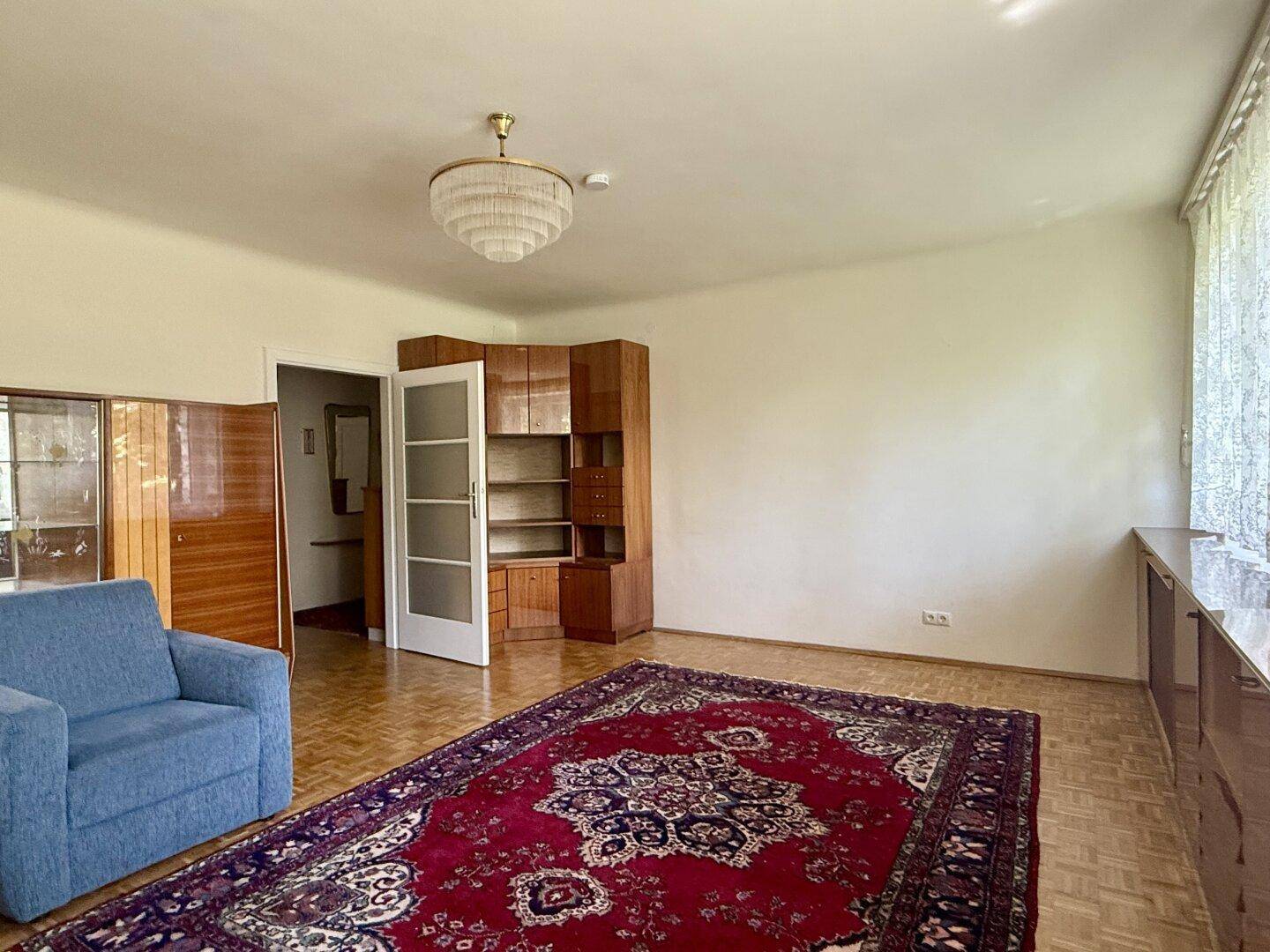 Wohnzimmer mit Parkettboden, Teppich und Holzschränken, die viel Stauraum bieten.