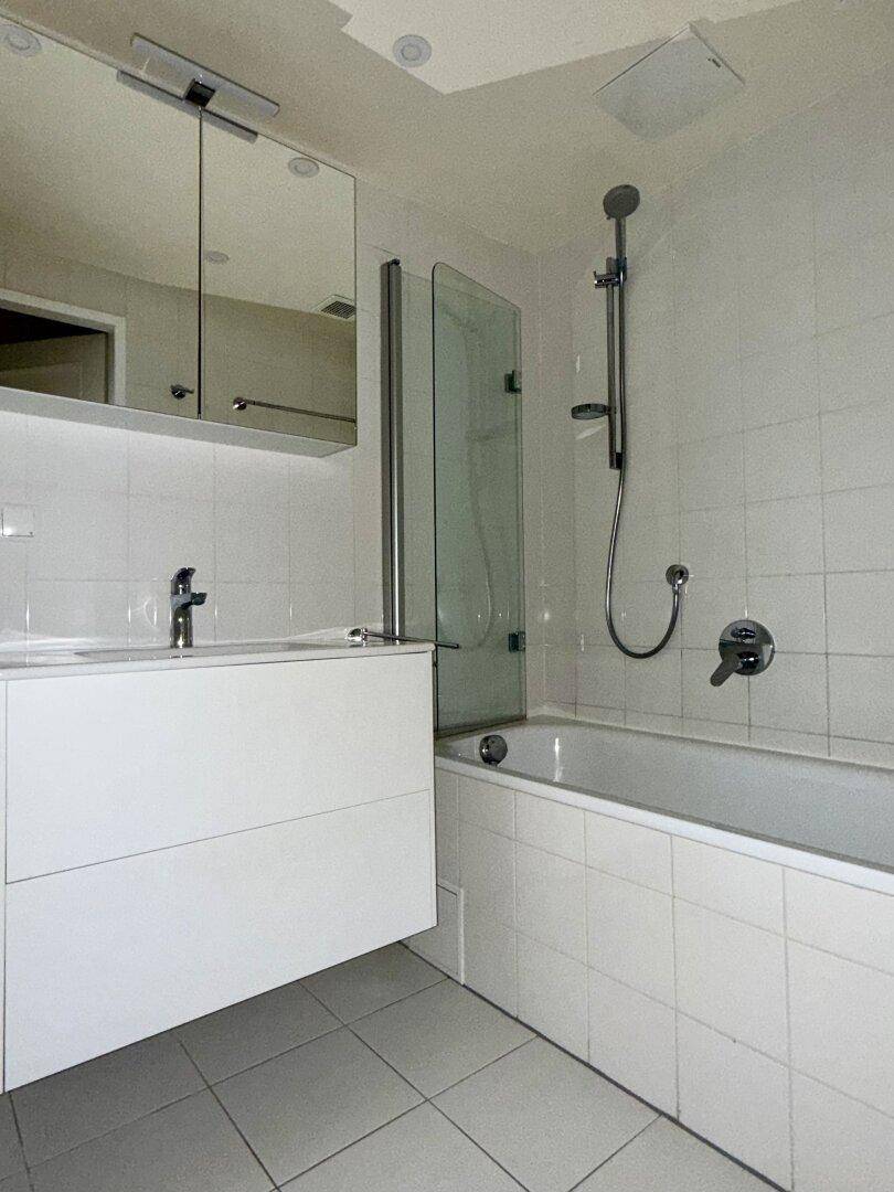 Modernes Badezimmer mit Badewanne, Duschabtrennung, Waschbecken und Spiegelschrank.