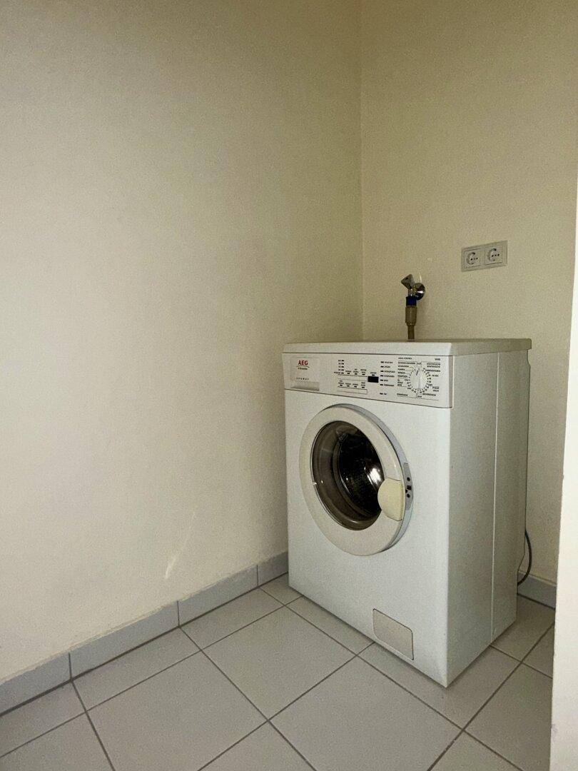 Praktischer Hauswirtschaftsraum mit Waschmaschine und Fliesenboden.