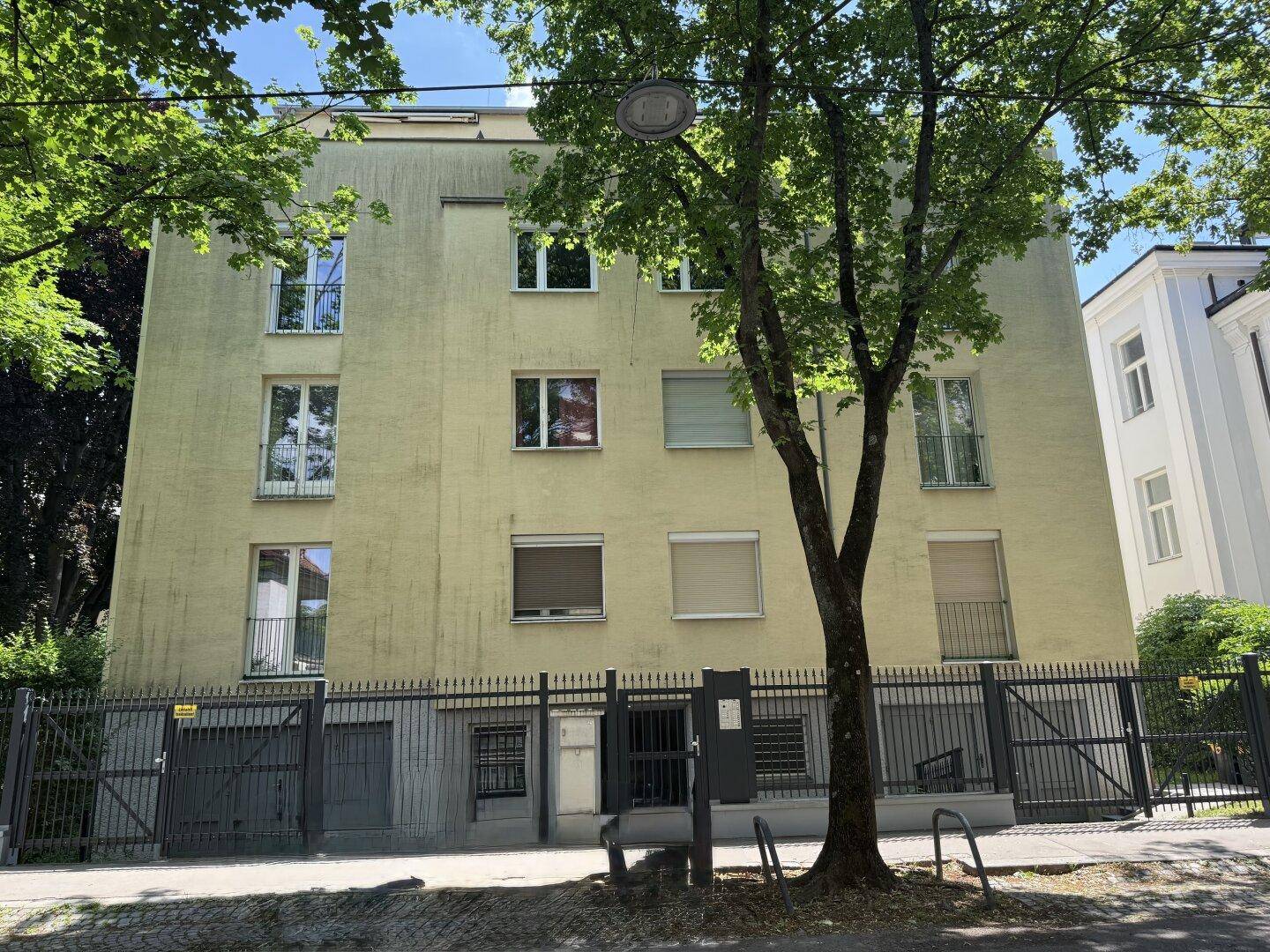 Mehrstöckiges Wohngebäude mit gelber Fassade, vielen Fenstern und Balkonen.