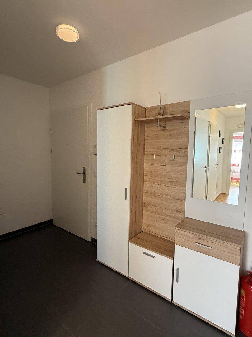Heller Flur mit praktischer Garderobe, Spiegel und Stauraum.