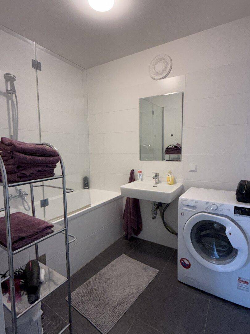 Badezimmer mit Badewanne, Duschfunktion, Waschbecken und Waschmaschine.