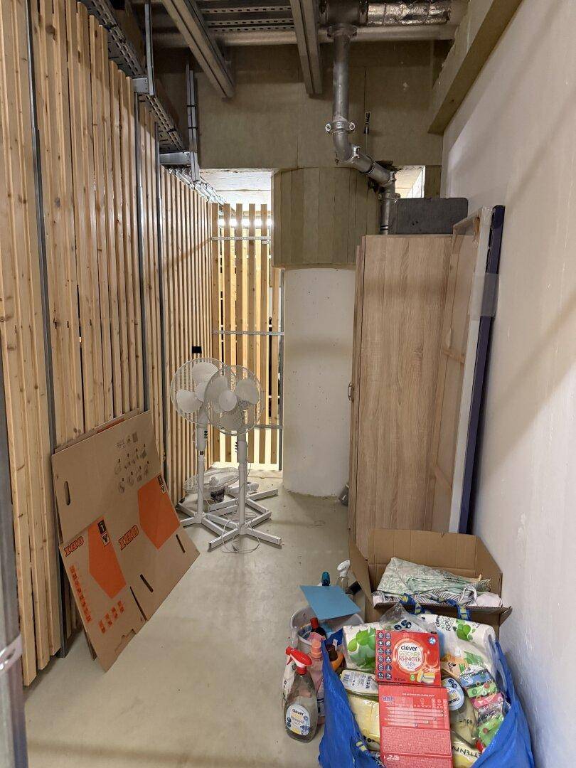 Abstellraum mit Holzverkleidung, sichtbaren Leitungen und Lagerflächen.