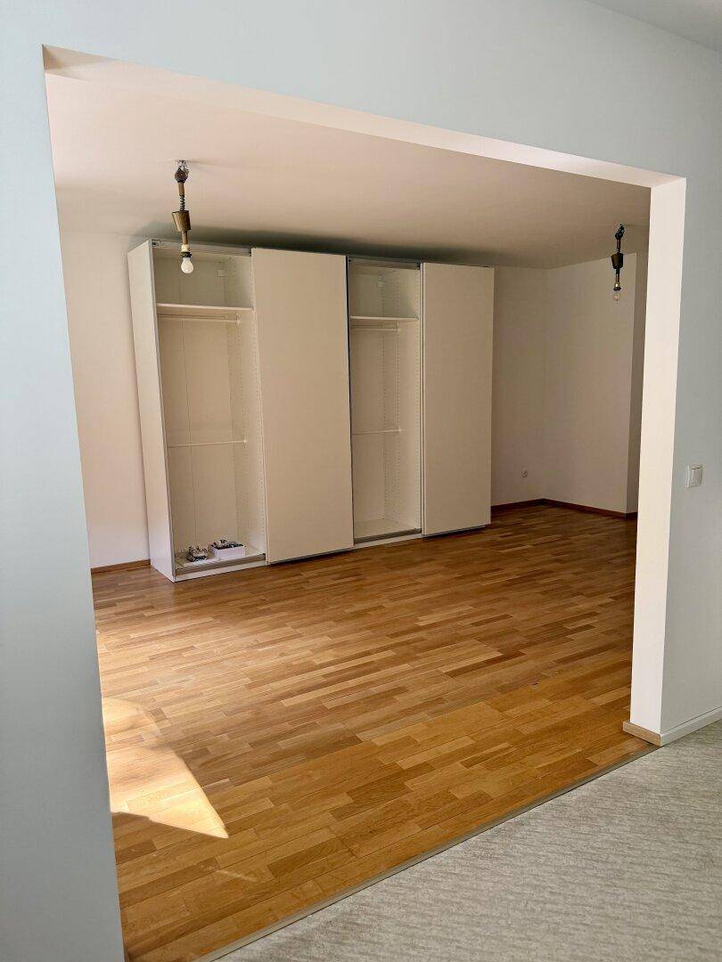 Heller Raum mit Parkettboden und großen weißen Schränken, ideal als Schlafzimmer oder Ankleidezimmer.