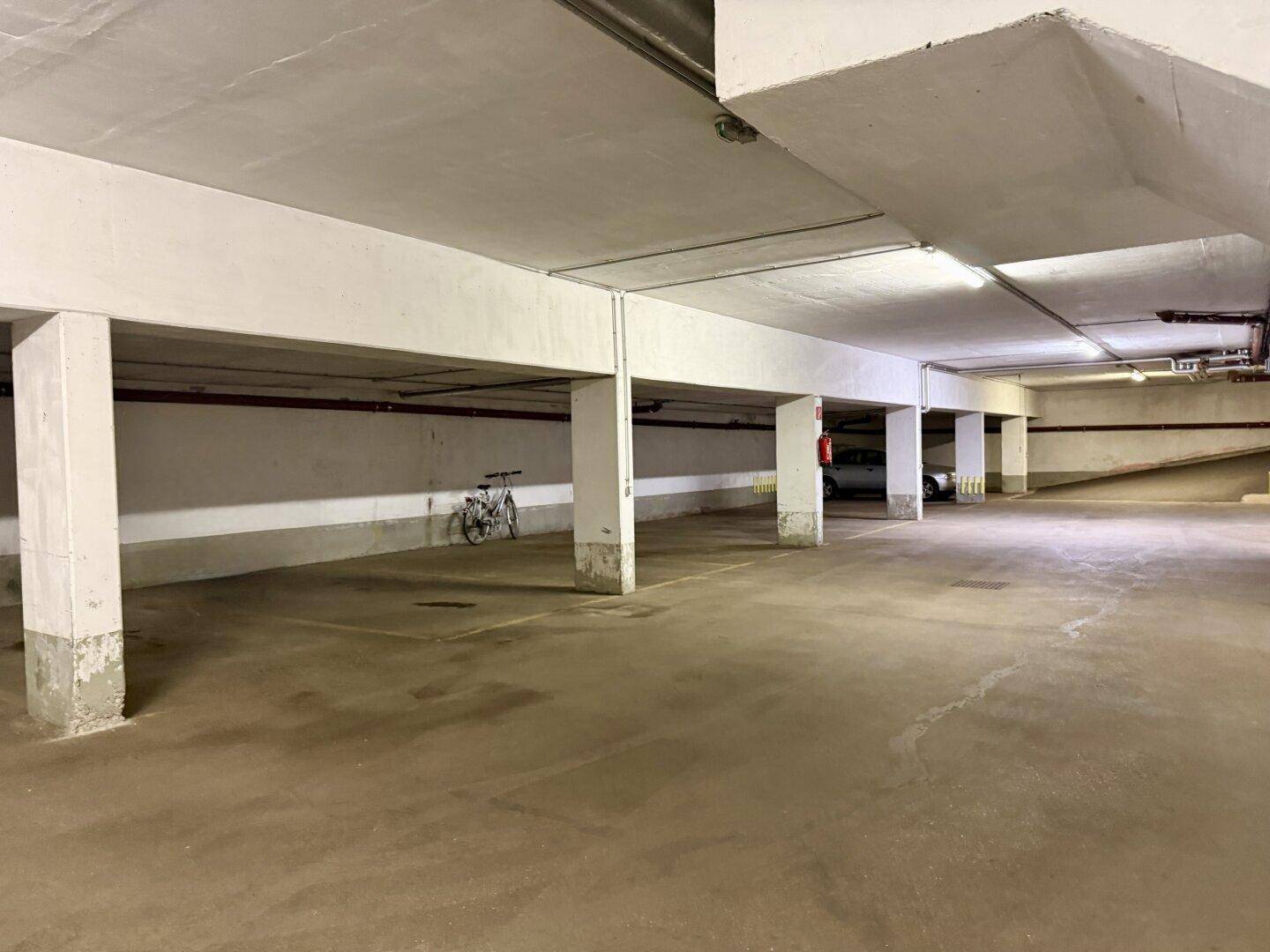Geräumige Tiefgarage mit Betonpfeilern und ausreichend Stellplätzen, inklusive Fahrradabstellmöglichkeit.