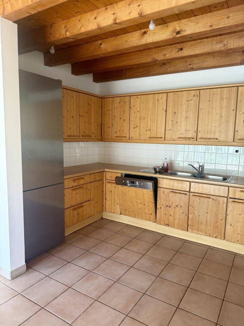 Funktionale Holzküche mit Kühlschrank, Spülmaschine und Fliesenboden.