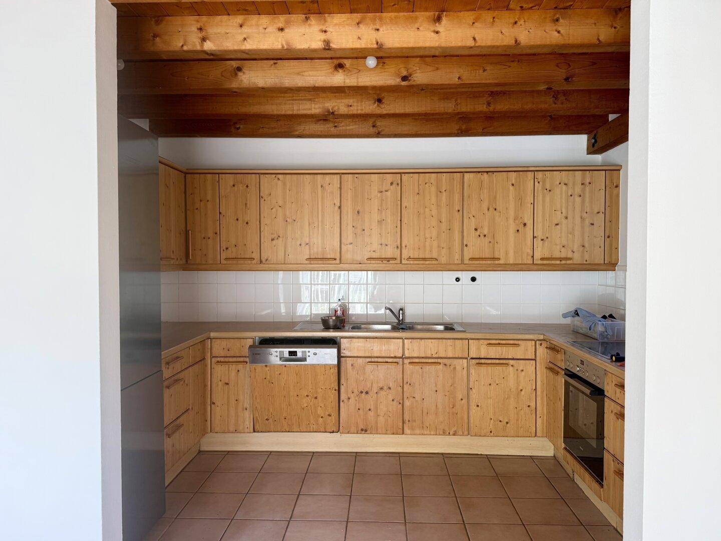 Gemütliche Holzküche mit Spülbecken, Herd und ausreichend Stauraum in den Schränken.
