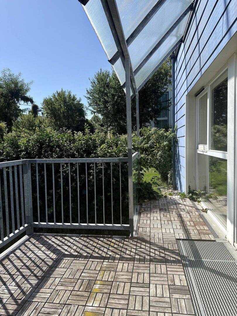 Geräumiger Balkon mit Holzboden und Überdachung, bietet einen schönen Blick ins Grüne.