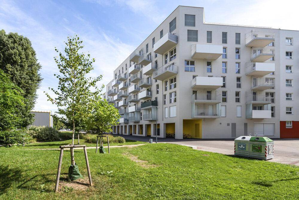 Außenansicht der modernen Wohnanlage mit gepflegter Grünfläche und Recyclingstation.