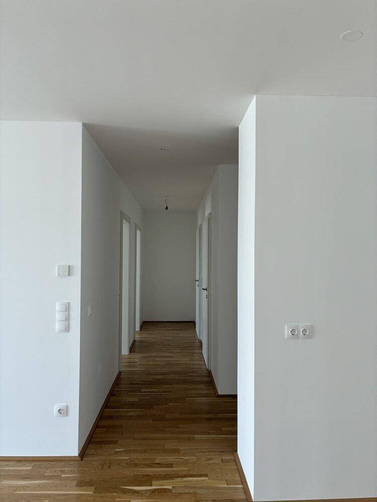 Langer, heller Flur mit Holzboden und mehreren Türen zu den angrenzenden Räumen.