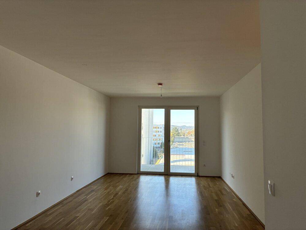 Geräumiges Zimmer mit Holzboden und Balkonzugang, bietet weite Aussicht.