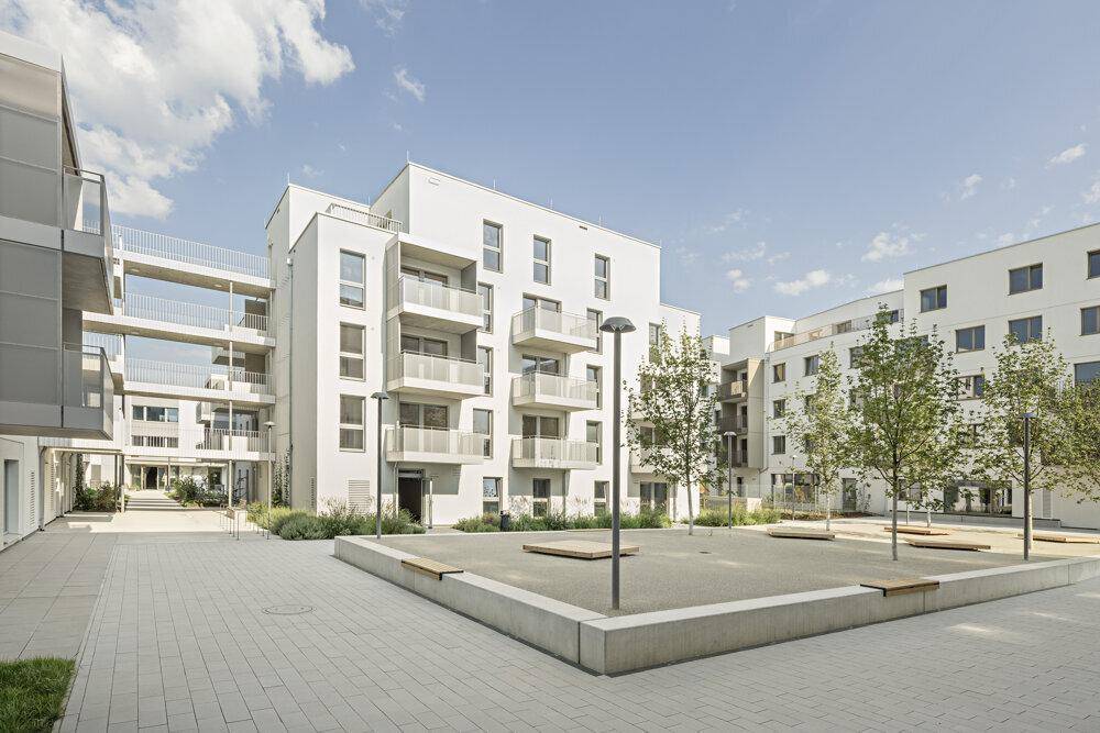 Weitläufige moderne Wohnanlage mit mehreren Gebäuden, Balkonen und einem gepflegten Innenhof.