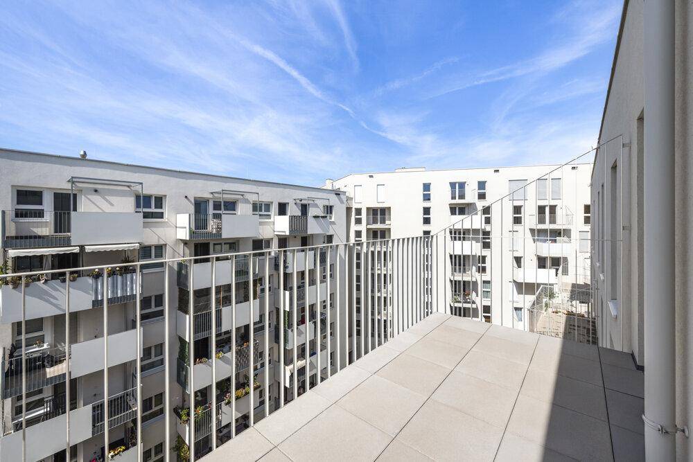 Geräumiger Balkon mit Fliesenboden und Blick auf die umliegenden Wohngebäude.