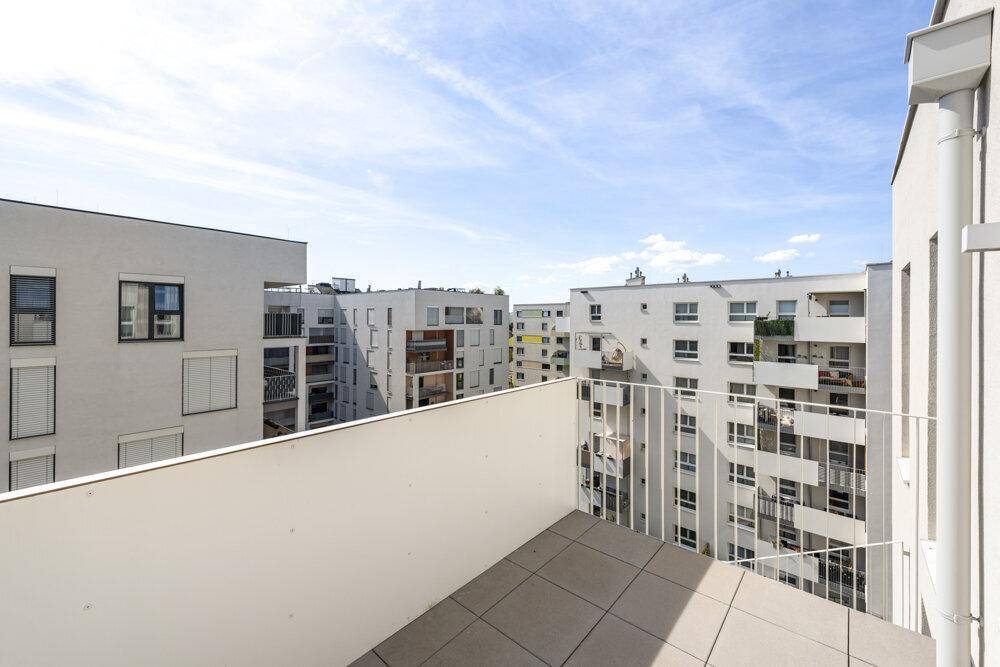 Geräumiger Balkon mit Fliesenboden und Blick auf den modernen Wohnkomplex.