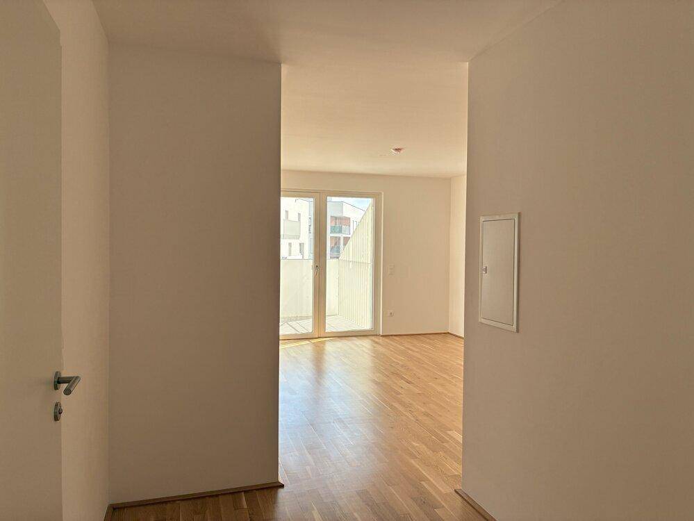 Heller Flur mit Blick in einen Wohnbereich, der durch große Fenster viel Tageslicht erhält.
