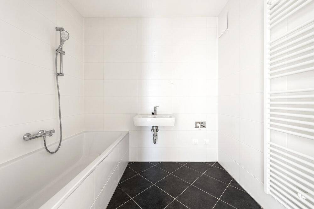 Modernes Badezimmer mit Badewanne, Dusche, Waschbecken und beheiztem Handtuchhalter.