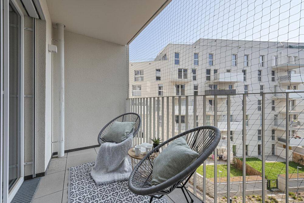 Möblierter Balkon mit Sitzgelegenheiten und Blick auf die umliegenden Gebäude.