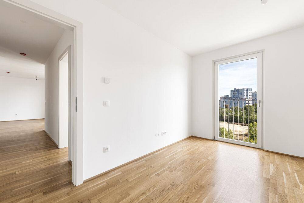 Helles Zimmer mit Holzboden und französischem Balkon, bietet einen Blick auf die Stadt.