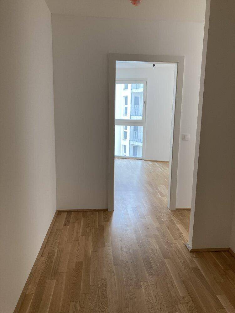 Heller Flur mit Parkettboden, der zu weiteren Räumen der Wohnung führt.