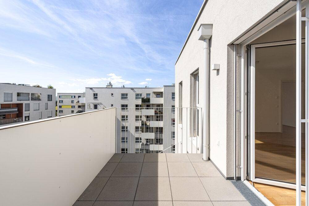 Heller Balkon mit Fliesenboden und Blick auf umliegende Wohngebäude.
