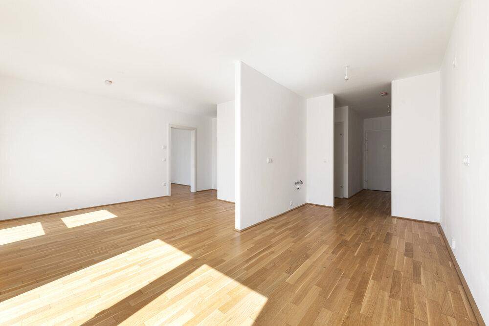 Geräumiger, heller Raum mit Holzboden und weiß gestrichenen Wänden.