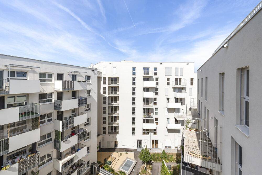 Blick auf eine moderne Wohnanlage mit mehreren Gebäuden und einem begrünten Innenhof.