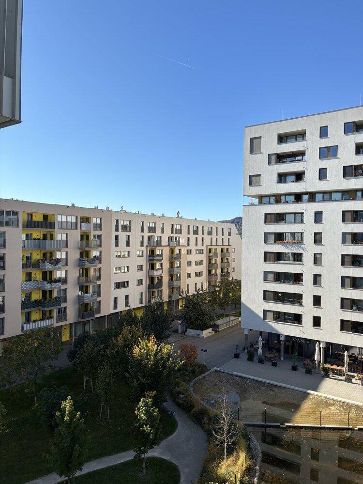 Moderne Wohngebäude mit Balkonen und einer gepflegten Grünanlage unter blauem Himmel.